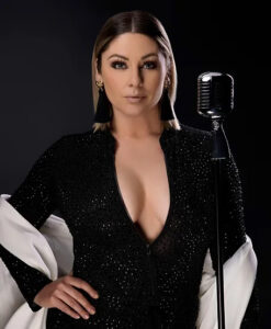 Professional singer, Emily Yates in elegant black attire standing next to a vintage microphone.